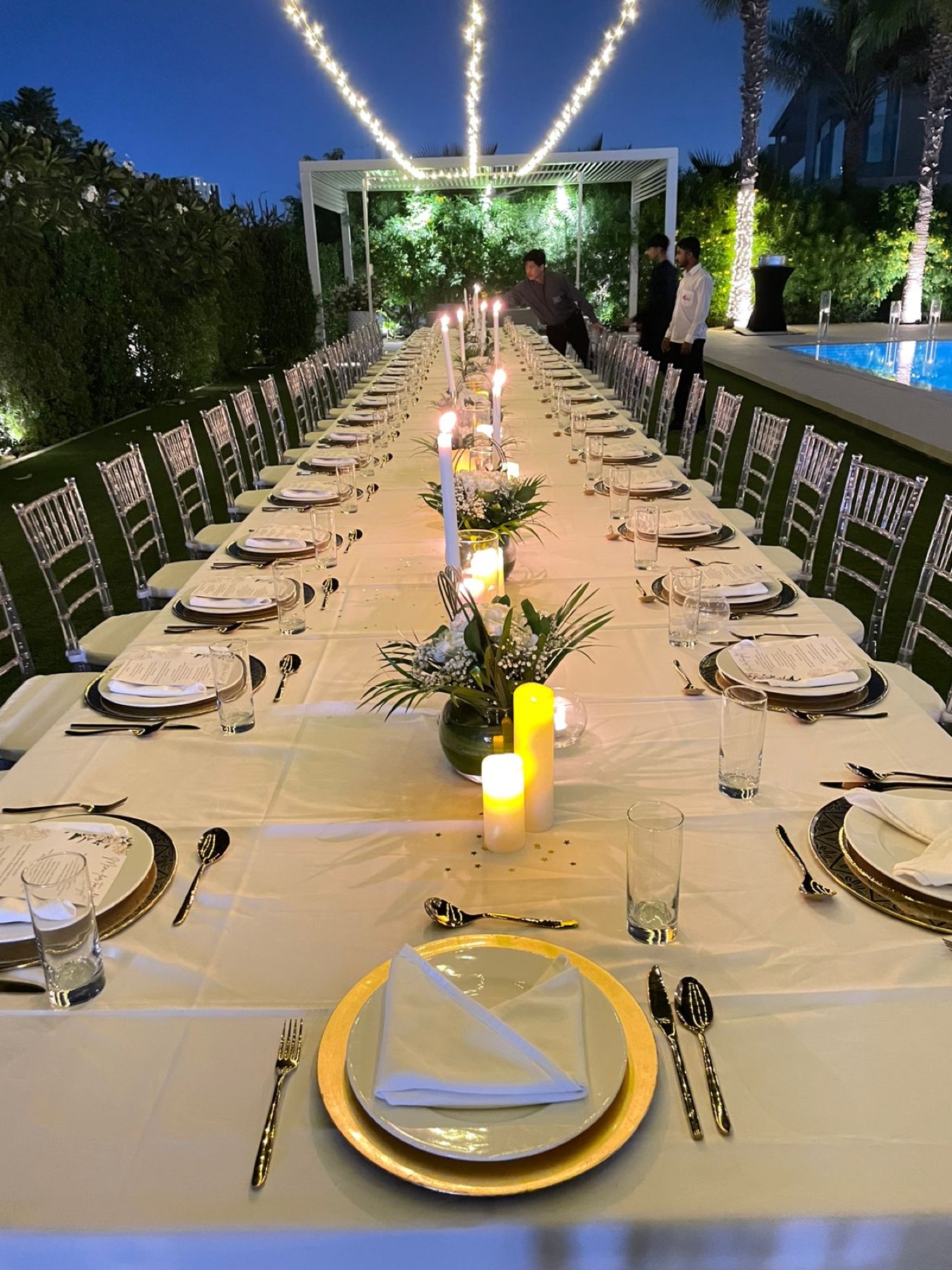 A candlelit long-table dinner set in a lush garden venue, styled by Cater Inc.